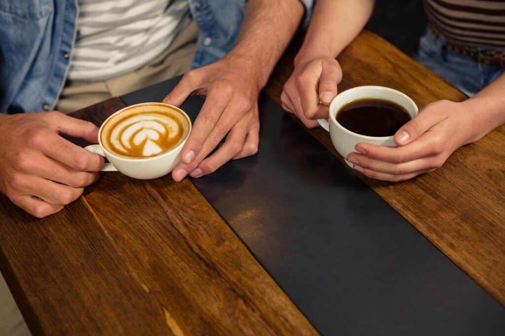 Closeup of a couple holding coffee in a cafe