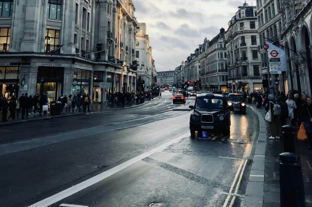 A damp street with taxis and shops in the buildings surrounding the street in the concept of services and amenities in Streatham for new residents.