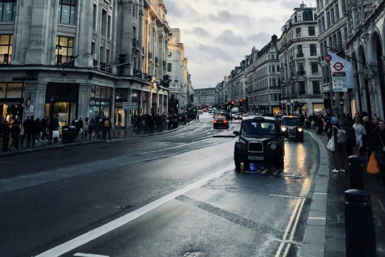 A damp street with taxis and shops in the buildings surrounding the street in the concept of services and amenities in Streatham for new residents.