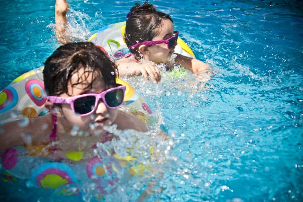 Kids in an outdoor pool with their floaties and sunnies