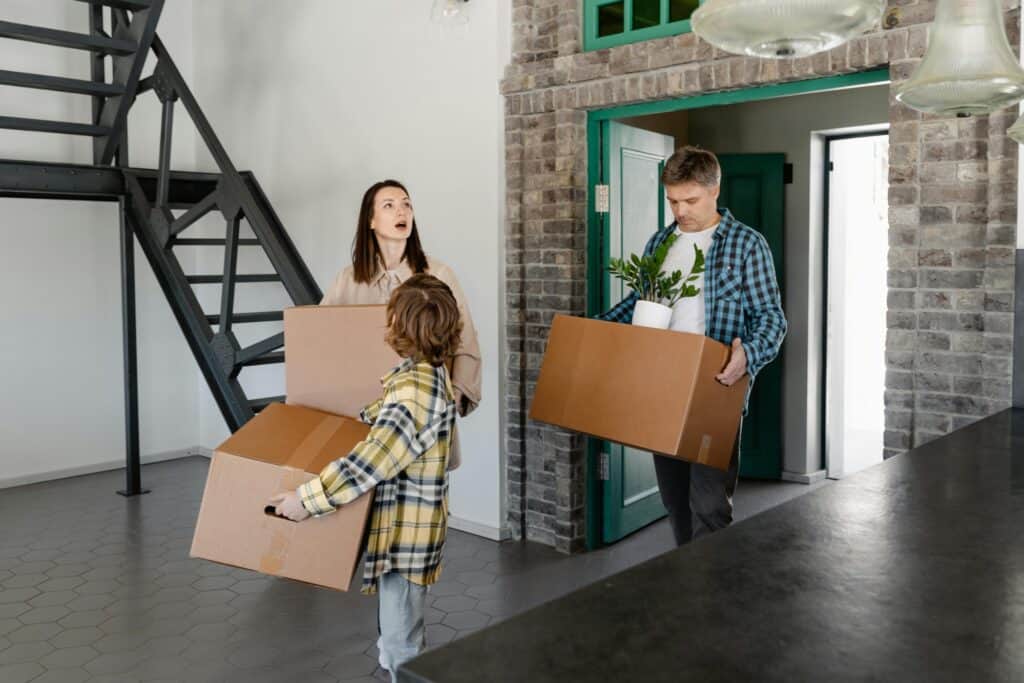 A young family is arriving at their new home while carrying boxes