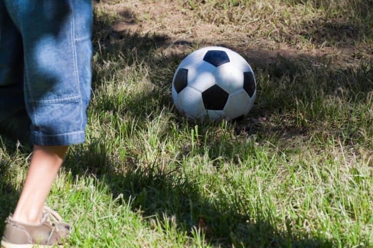 Cropped image of a boy playing football in a Streatham's green space in the concept of 'best parks and green spaces in Streatham'.