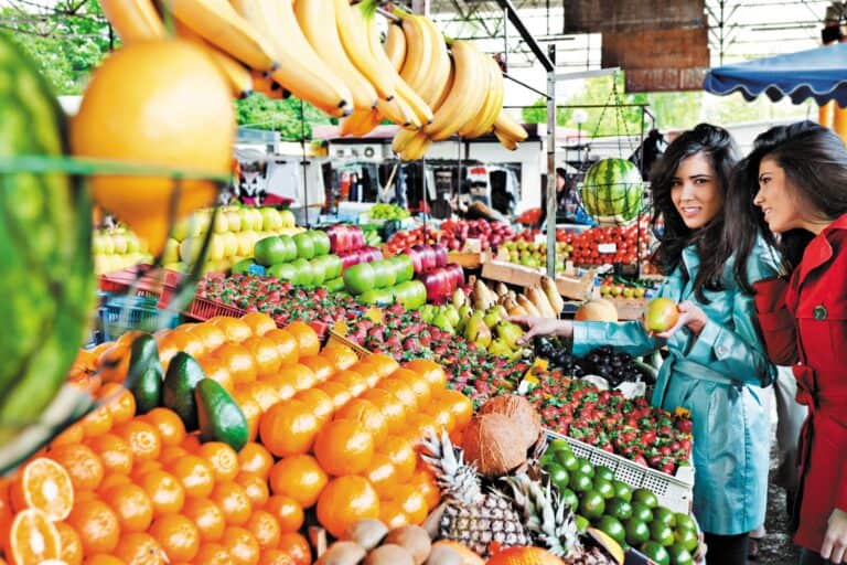 Two women in a fruit stall in a farmers' market in the concept of 'best local shops and markets in Streatham'.