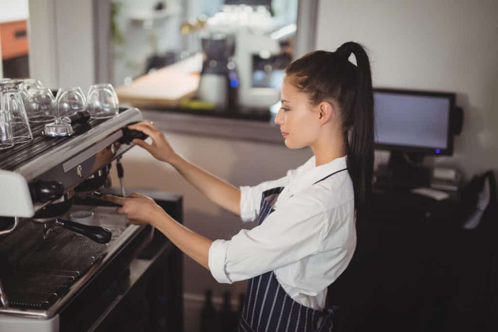A waitress preparing espresso at a restaurant