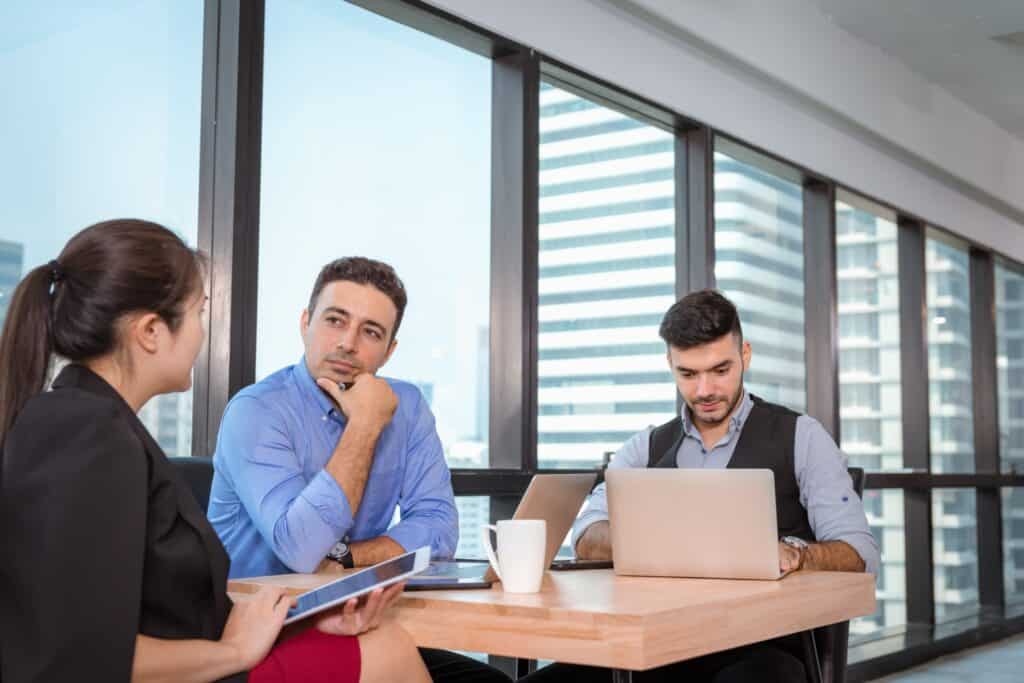 Two male employees speaking with the office removals representative for initial consultation